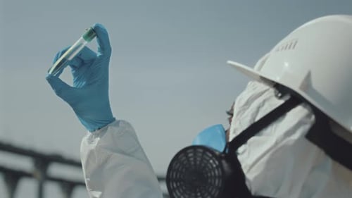 Ecologistas con uniforme protector examinan un tubo de ensayo con muestra