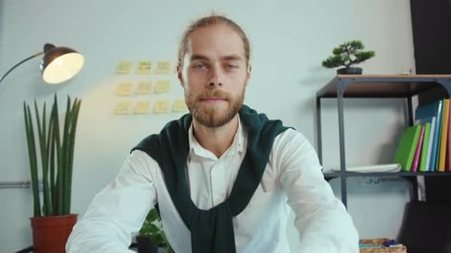 Young Man Working at Desk in Office Speaking