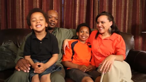 Happy Family Smiling on Brown Couch Together