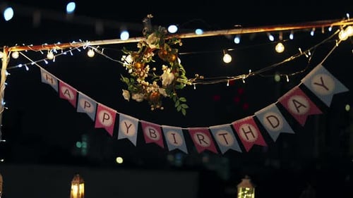 Баннер 4K Happy Birthday, вырезанный из бумаги, висит на столбе на открытой крыше.