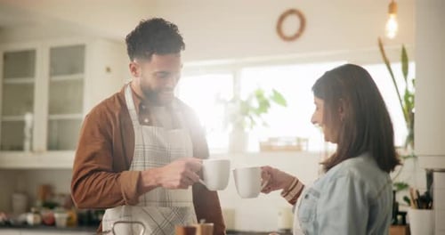 Young Couple Toasting Mugs in Bright Kitchen