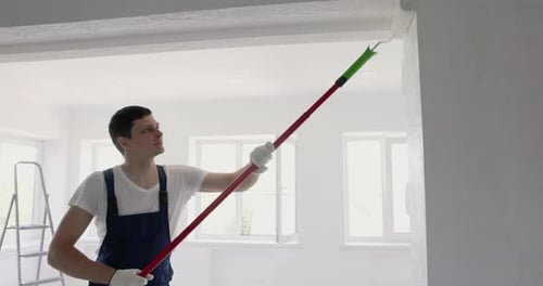 Mann malt Wand in weißer Farbe mit Rolle