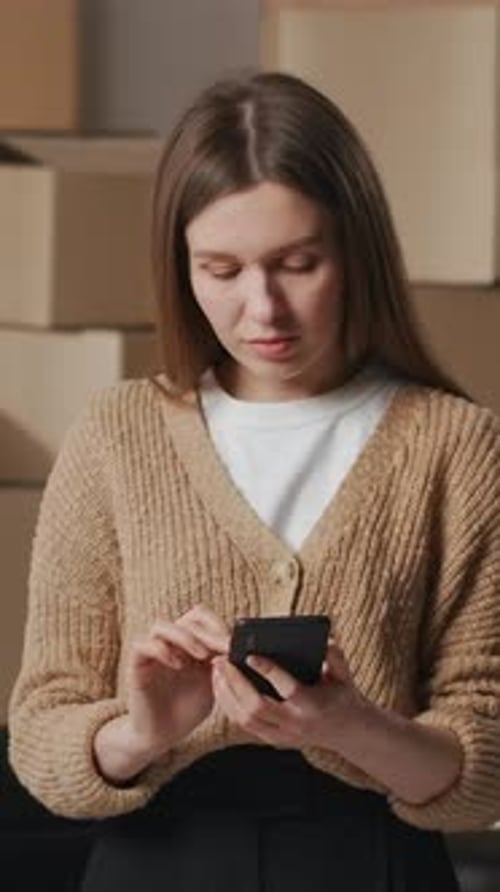 Young Woman Using Phone Indoors with Boxes