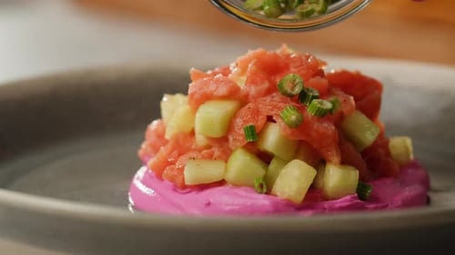 Chilean Salmon Tartar Seviche with Avocado and Cucumber on Purple Cream Cheese Adding Green Onion on