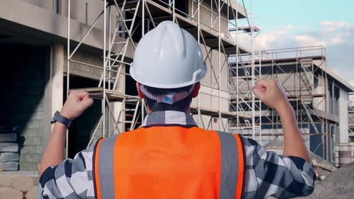 Back View Of A Male Engineer Raising His Hands Celebrating While Working At Building Site