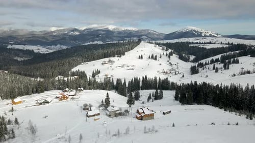 Winterlandschaft mit kleinen ländlichen Häusern in abgelegener Siedlung zwischen schneebedecktem Wald in Kälte