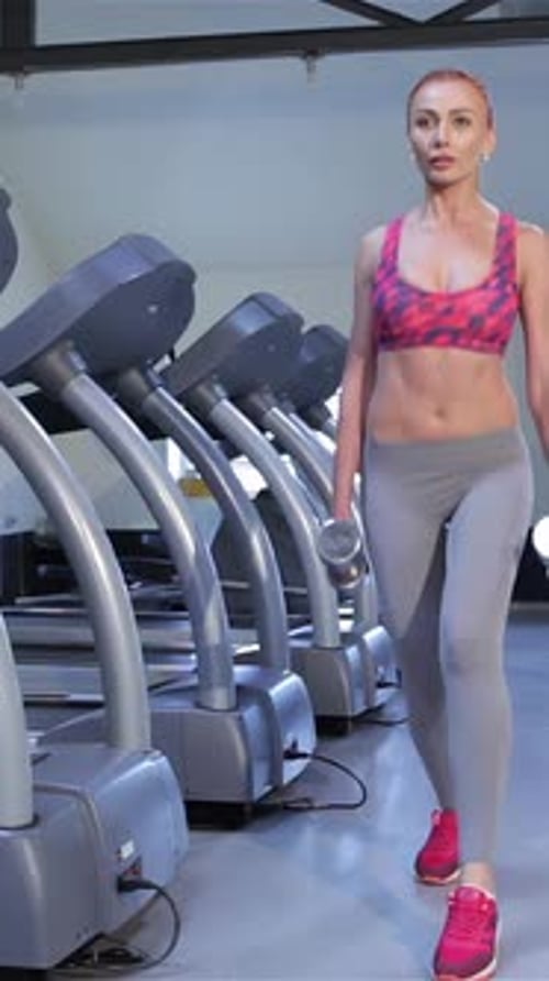Determined Woman Performs Stepup Exercise with Dumbbells at Fitness Center