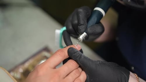 Manicurist Shaping Fingernail with Drill in Beauty Salon