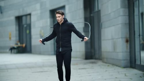 Fit Man Training Jump Exercise on Skipping Rope on Street Workout. Male