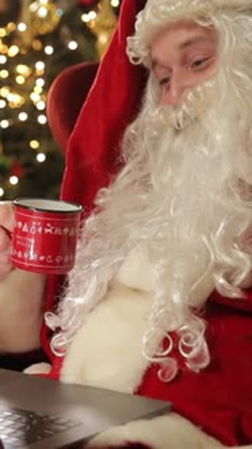 Santa Claus with Laptop and Coffee Near Christmas Tree Vertical Video