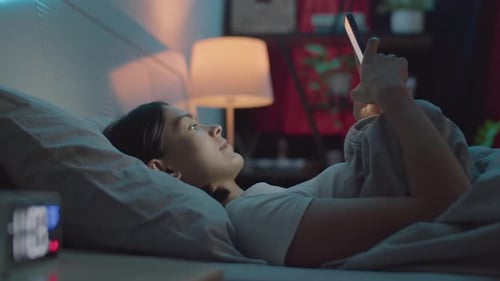 Woman Messaging on Phone in Bed at Night