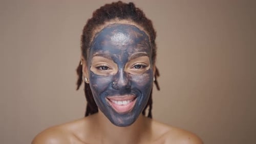 Smiling Woman with Clay Facial Mask Application