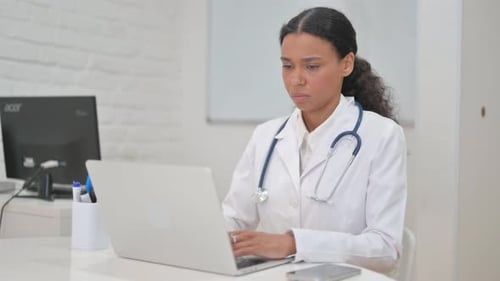African Female Doctor Typing on Laptop