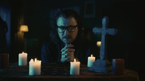 Man Praying at Night with Candles and Cross