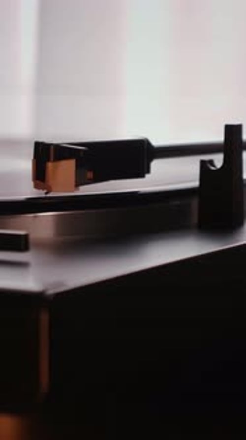 Needle slides smoothly on rotating black vinyl record, close up. Vertical video