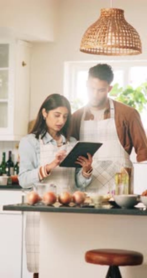 Young Couple Cooking Together in Kitchen with Tablet