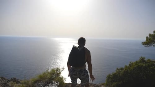 Man Stands on Cliff Overlooking Ocean View