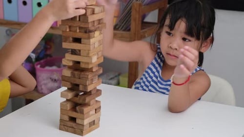 Cute Asian siblings having fun playing Jenga together.