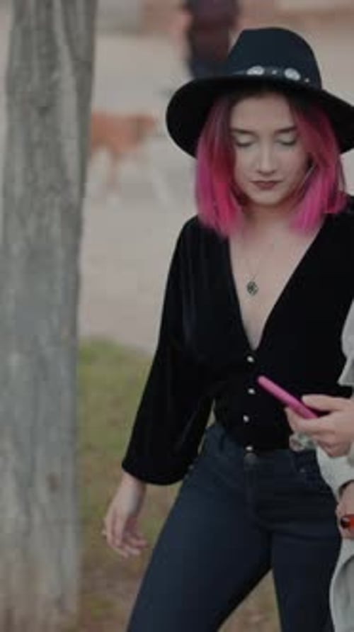 Two Young Women Walk and Talk in Park