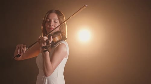 Woman plays violin in atmospheric setting