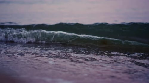 Las olas del océano salpican la playa de arena en. De cerca ondeando el agua del mar