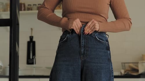 Woman Putting on Jeans in Modern Kitchen