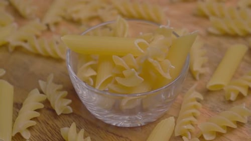 Bowl of Dry Pasta on Wooden Board