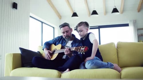 Dad teaches son to play acoustic guitar