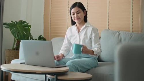 Junge schöne Frau arbeitet zu Hause mit ihrem Computer.
