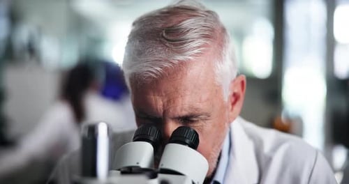 Mature Scientist Using Microscope in Bright Laboratory