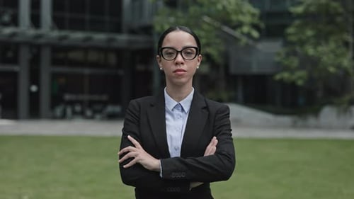Charming Serious Businesswoman Standing Near the Work Place Wearing Black Glasses and Crossing Her