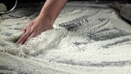 Hand Placing Flour on Table for Baking Preparation