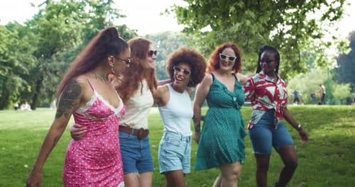 Um grupo de moças multiétnicas caminhando no parque enquanto se abraçam,