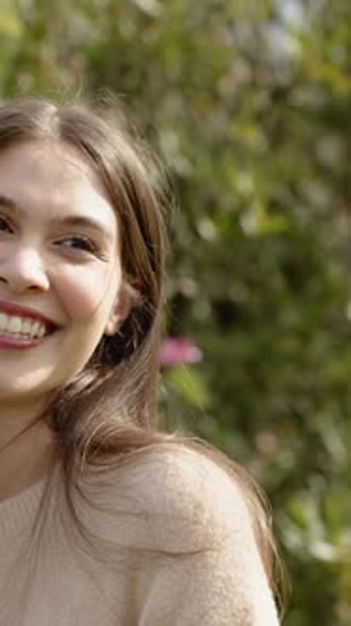 Vidéo verticale : Femme souriante en pull en tricot pâle accueillant un ami arrivant dans le parc, cerceau doré