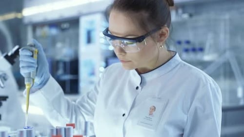 Woman Scientist Pipetting Sample in Laboratory Setting