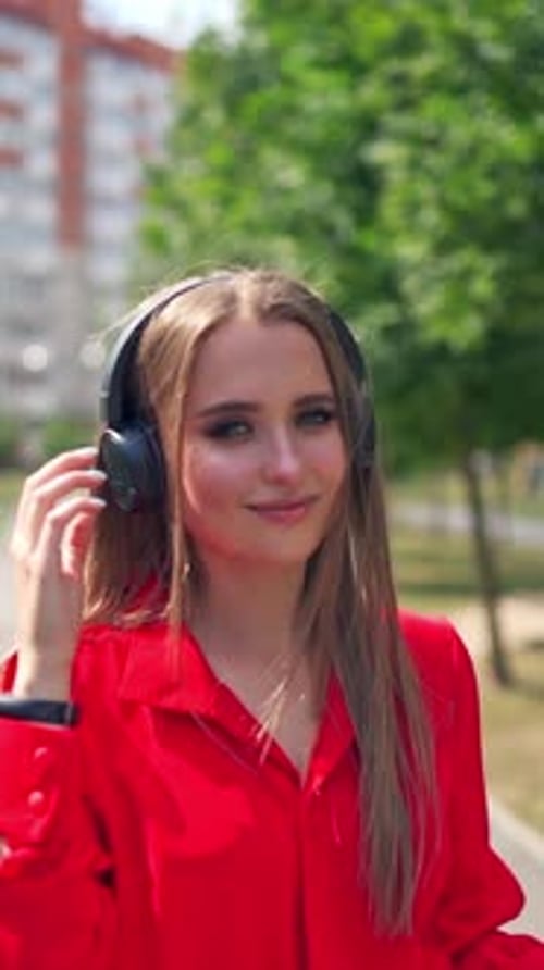 Lovely girl outdoors. Portrait of a young woman with headphones.