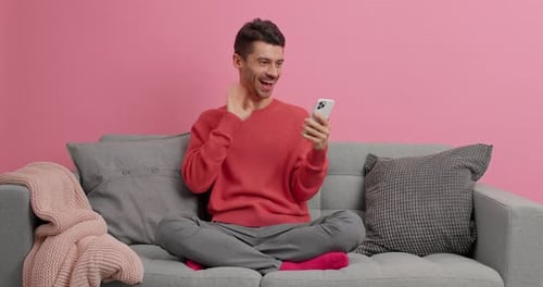 Cheerful man video calling while sitting cross legged
