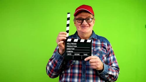 Amable y divertido hombre mayor aplaude en claqueta durante la producción de la película