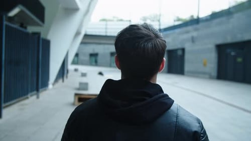 Back View of Man Walking on Urban Street in Black Jacket. Closeup