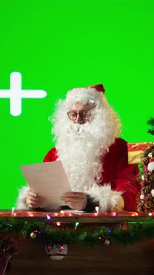 Vertical Video Father Christmas Reads Letters and Sitting Against a Big Green Screen