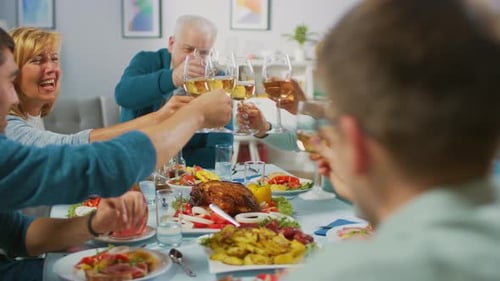 Family and friends toasting at dinner table indoors