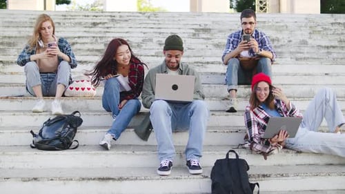 Young Adults Relaxing on Stairs with Devices