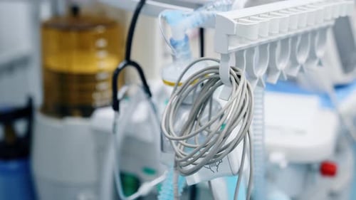 Folded wire from the medical equipment hanging in the ward. Lung ventilator machine at backdrop.