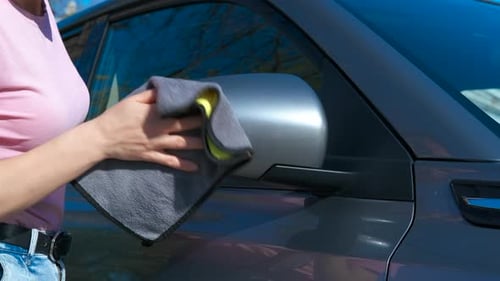Mujer limpiando las ventanas laterales del coche