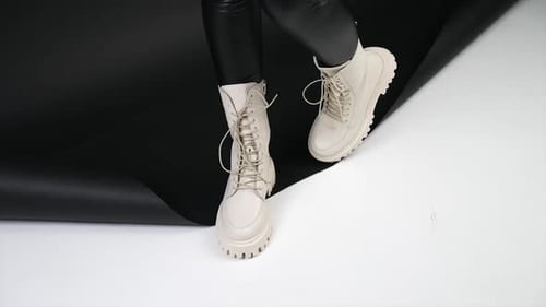 Milk-white tractor boots with laces demonstration. Female model in studio