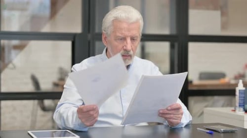 Senior Man Reads Document and Gives Thumbs Up
