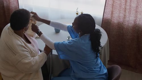 Caregiver Assisting Senior Lady with Disability during Daily Checkup