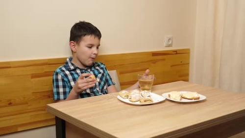 Boy Eats Pastries and Sandwiches at Kitchen Table