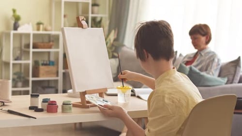 Focused Child Painting on Canvas at Home