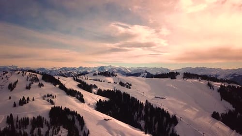 Snowy mountains in low clouds and blue sky at sunset in winter. Panoramic landscape with beautiful s